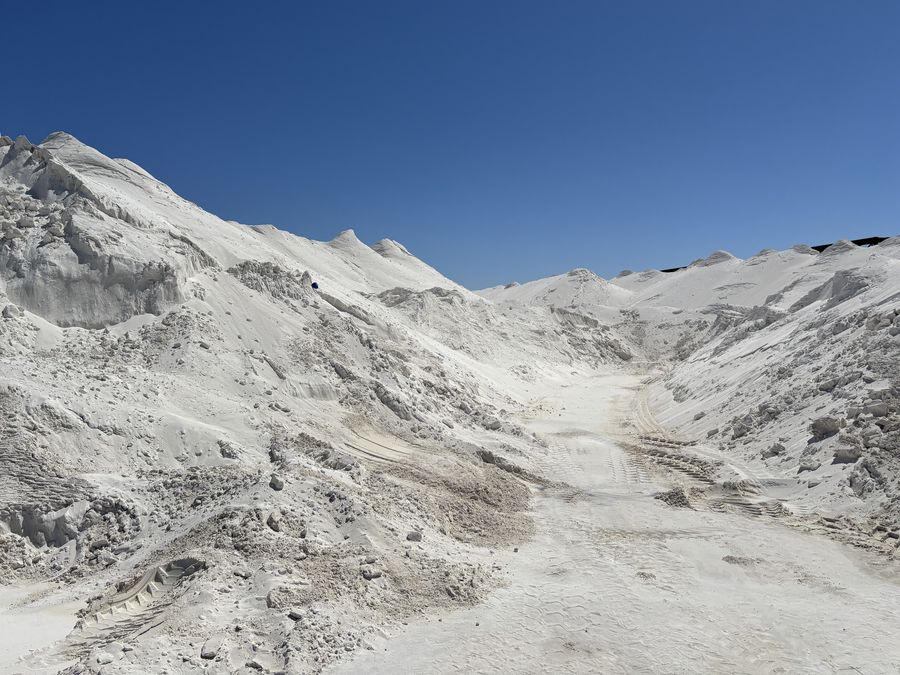 A haul lane running between two white aragonite stockpiles, with tyre tracks in the floor